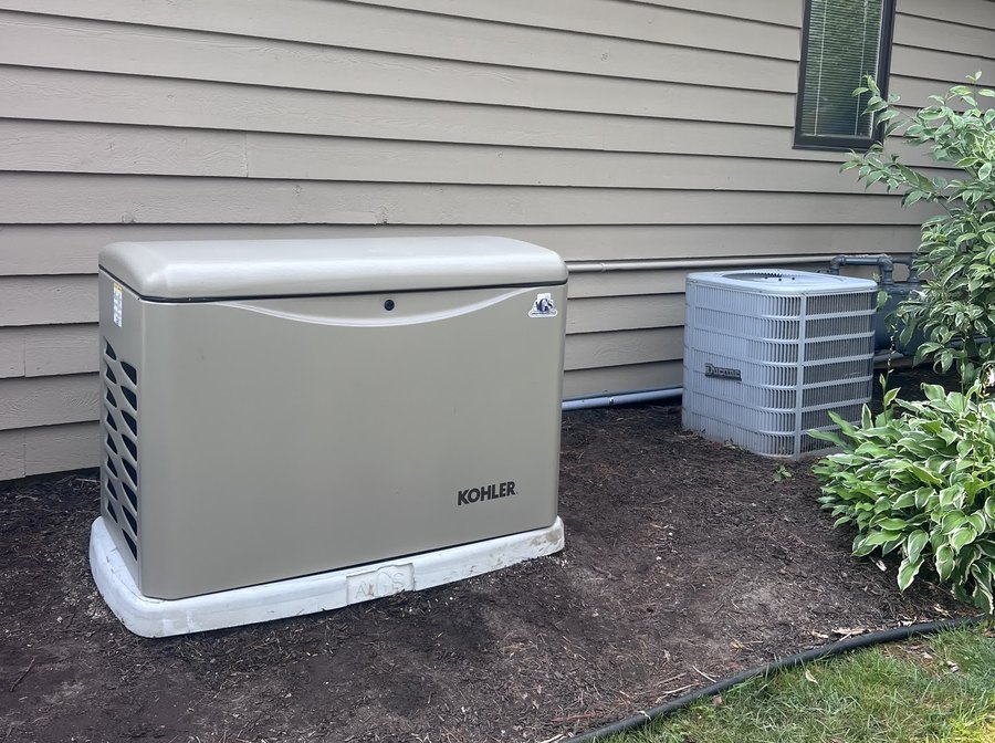 Kohler standby generator on an AGS-stamped concrete pad next to the air conditioning unit at a lap-sided home